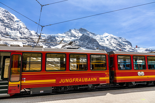 Train carriage of the Jungfraubahn train with the snow and glacier covered Junfrau mountain peak in the background.