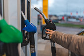 Close-up of a young woman holding a black (diesel) gas nozzle at a gas station