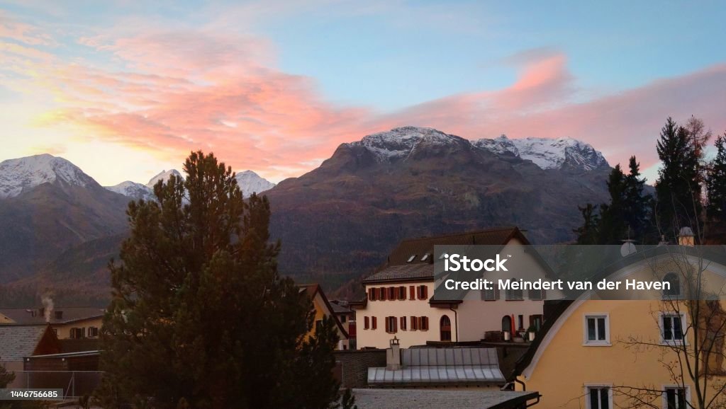 Pink clouds over the Swiss Alps Colourful clouds over the mountains in Engadin, Switzerland at sunrise. View is to the south-southeast from the town of Samedan, close to St.Moritz. Atmosphere Stock Photo