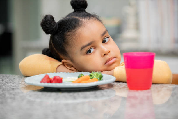 Upset toddler refuses to eat healthy meal because she is a picky eater stock photo