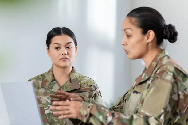 Photo of Female soldier meeting in office with commanding officer. Women are wearing camo clothing