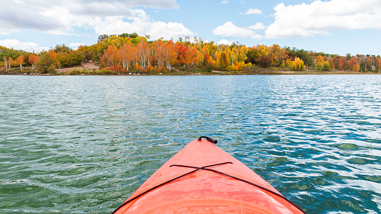 Orange Kayak on the lake points to the fall-colored aspen trees on the shore