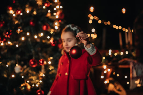 Portrait of a little girl decorating Christmas tree outdoors, in her backyard.