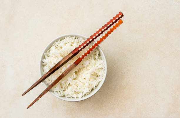 High angle view of cooked white rice ready to eat with japan style stick.Image made with natural light from window using tripod with a 24 megapixels full frame camera and 50 mm lens f/stop 1.8