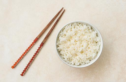 High angle view of cooked white rice ready to eat with japan style stick.
Image made with natural light from window using tripod with a 24 megapixels full frame camera and 50 mm lens f/stop 1.8
