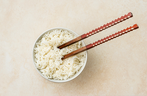 High angle view of cooked white rice ready to eat with japan style stick.\nImage made with natural light from window using tripod with a 24 megapixels full frame camera and 50 mm lens f/stop 1.8