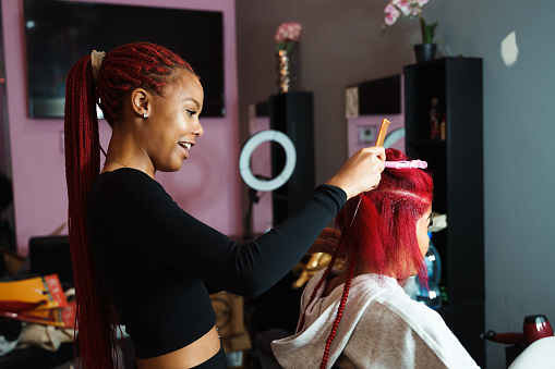 Hair stylist braiding a clients hair in a beauty salon.