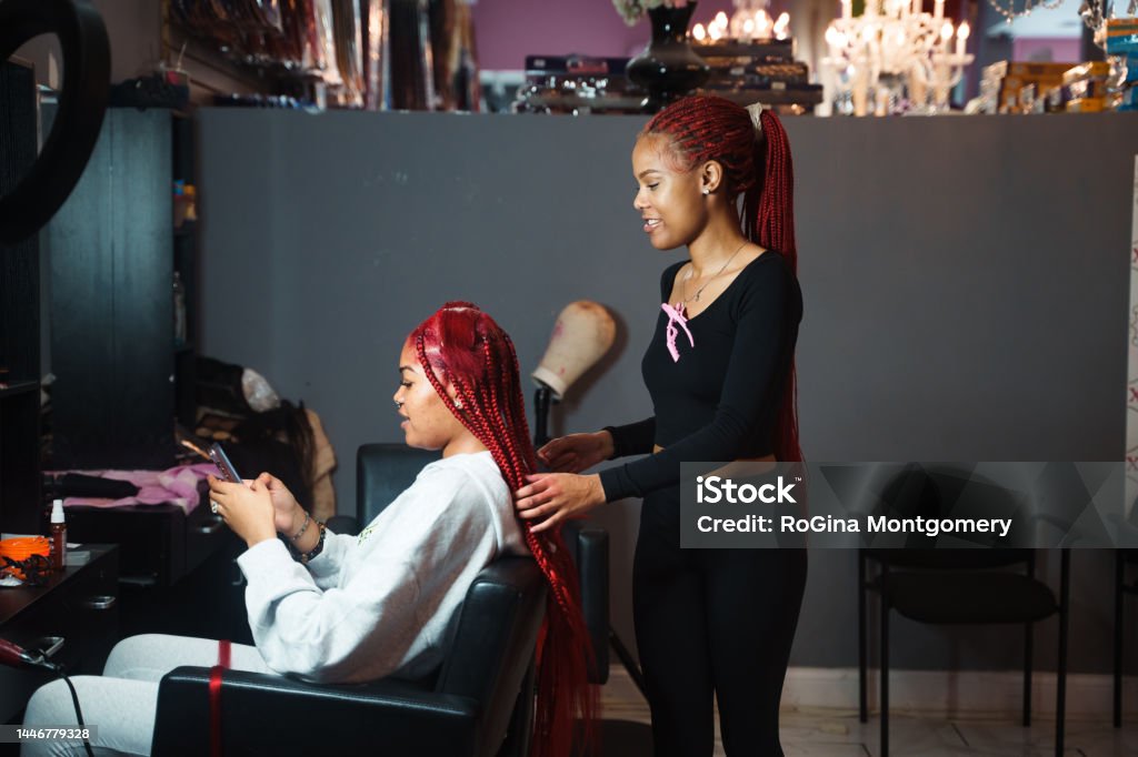 Stylist Braiding Hair in a Salon Hair stylist braiding a clients hair in a beauty salon. Braided Stock Photo