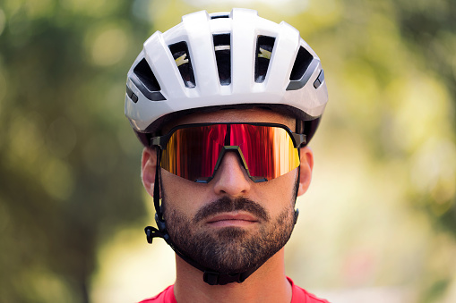 portrait of a young cyclist wearing a helmet and cycling goggles looking at camera with a defiant attitude