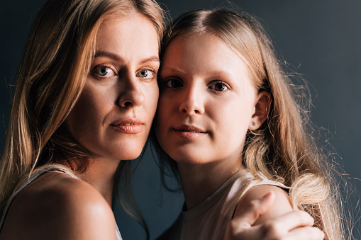 The love between a mother and daughter is forever: a charming Caucasian mother and her cute daughter looking at camera. (studio shot, close up view)