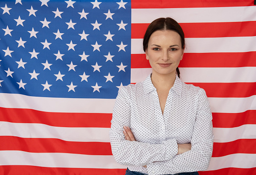 Young english teacher woman smiling on american flag background, education concept.