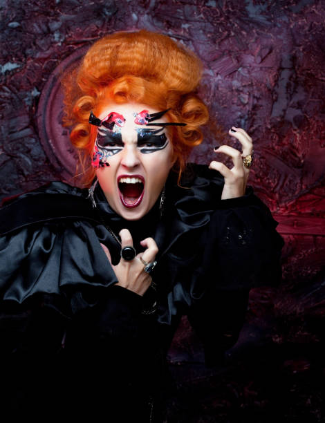 istock Young redhead woman dressed as a witch, posing over dark background. Carnival makeup and hairstyle. Close up. 1446789326