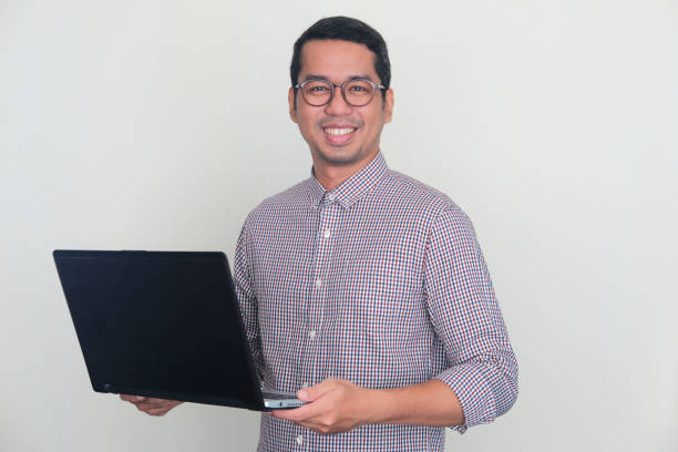 istock Adult Asian man smiling confident while holding a laptop computer 1446790693
