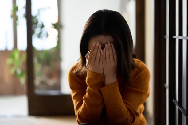 Photo of woman covering her face with both hands