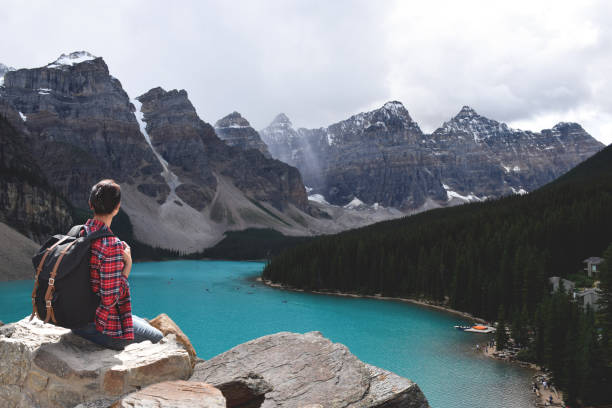 istock Woman with backpack sitting on mountain top rock enjoying the view 1446792442