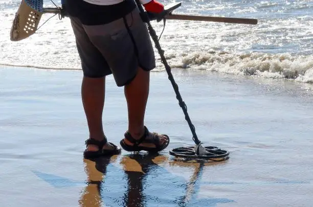 A Man with a metal detector on a sandy sea beach