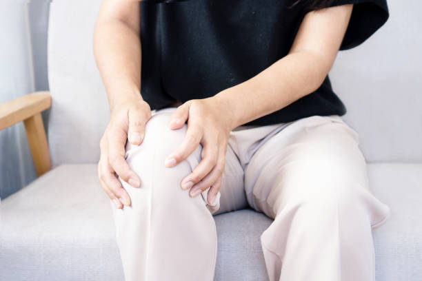 senior man suffering from knee pain sitting on sofa closeup senior man suffering from knee pain sitting on sofa obese joint pain stock pictures, royalty-free photos & images