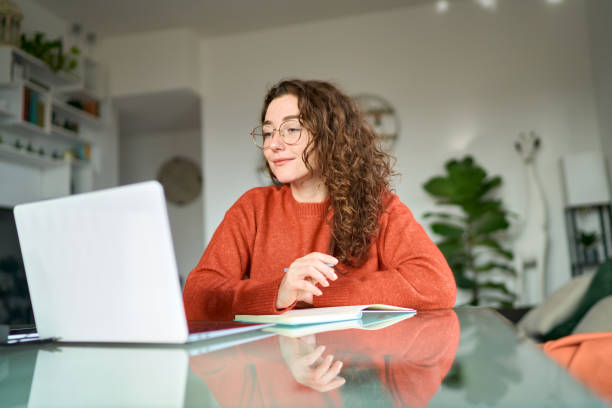 istock Young female student using laptop watching online webinar writing at home. 1446806050