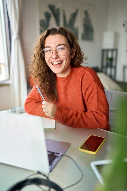 istock Happy young woman student laughing using laptop sitting at desk studying online. 1446806054
