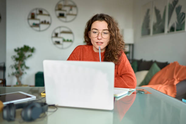 istock Young woman student looking at laptop watching online webinar learning at home. 1446806062