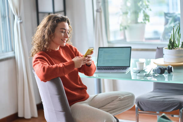 istock Young smiling woman using mobile phone studying or working at home. 1446806064
