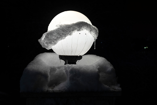 Street lamp, covered with ice and snow in winter park at night, Khimki, Moscow region, Russia.