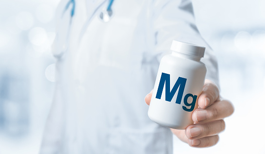 Magnesium, Mg. Mg supplements for human health. Doctor recommends taking Magnesium. Doctor gives Magnesium vitamin. Essential vitamins and minerals for humans. Doctor hold bottle with supplement Mg