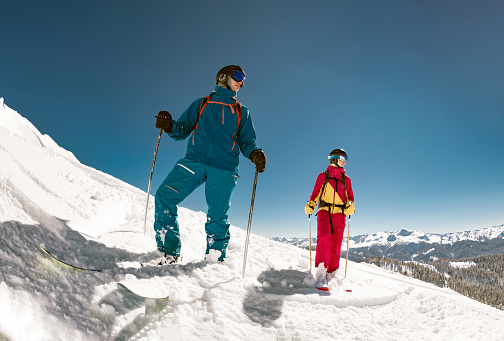 Two young skiers are standing on ski slope.