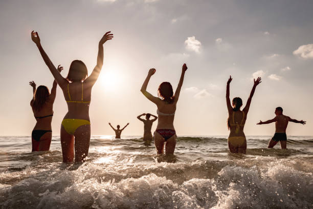 istock Group of young friends at sunset beach 1446817751