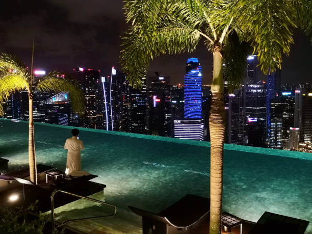 Tourists relaxing at the 150 m infinity swimming pool with view of Singapore cityscape, set on top of the world's largest public cantilevered platform at Marina Bay Sands, an integrated resort fronting Marina Bay.