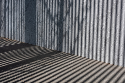 abstract shadow batten of lath and morning light on white concrete wall texture background