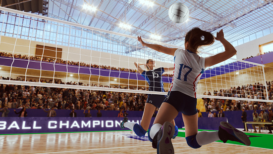 Female volleyball player spiking the ball during game at sports court