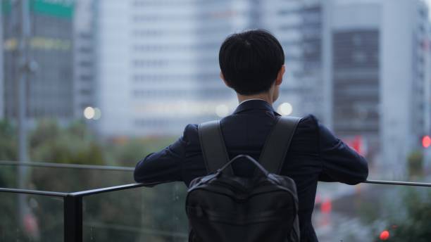 Businessman sheltering from rain and looking at cityscape