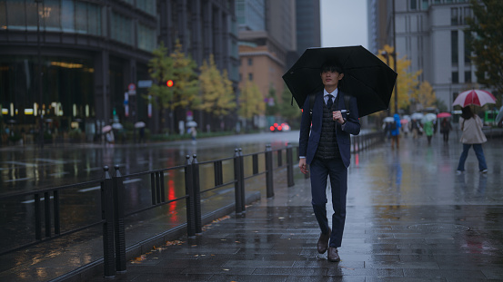 A businessman is commuting in the rain in the city.