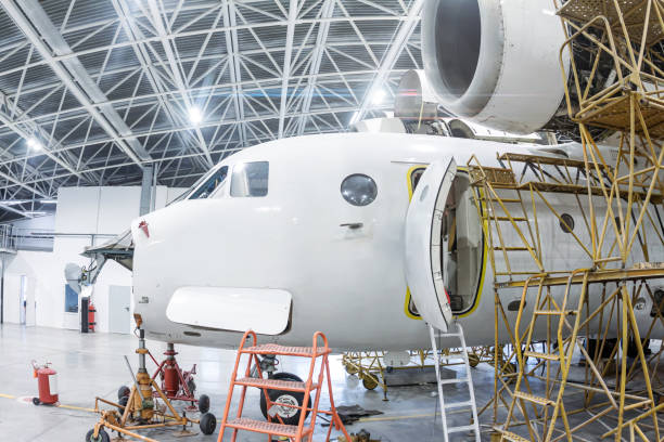Close-up white transport airplane in the hangar Close-up white transport airplane in the hangar. Aircraft under maintenance. Checking mechanical systems for flight operations fuselage stock pictures, royalty-free photos & images