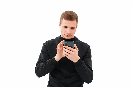 a man in black with a smartphone in his hands on a white background. the concept of sms, correspondence in social networks, games, online dating and shopping. modern communication.