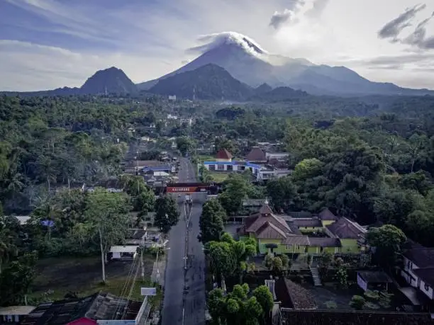 A scenic view of the forested city Kaliurang in Indonesia with the active volcano Mount Merapi in the background