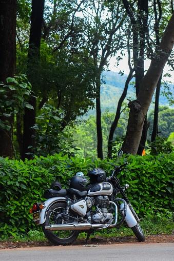 chikmagalur, India – June 03, 2022: A closeup of Royal Enfield classic 350 bike in hilly mountain road with nature background