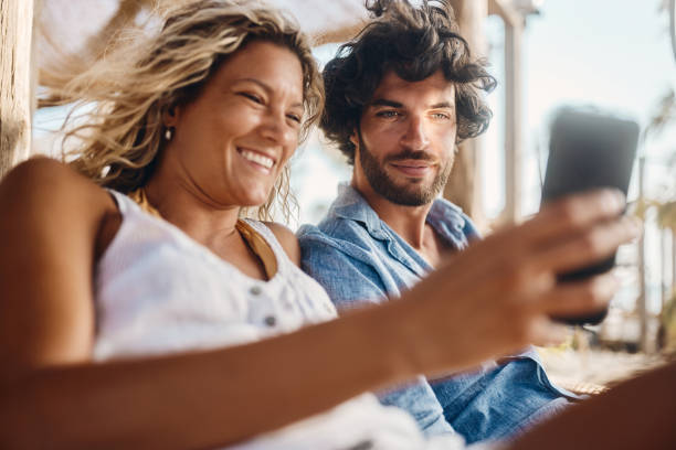 istock Happy couple using mobile phone on the beach. 1446832737