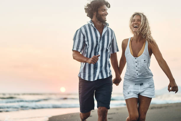 istock Carefree couple having fun while running on the beach at sunset. 1446832831