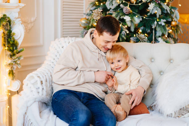 istock happy dad with his young son on the couch by the Christmas tree. 1446833548