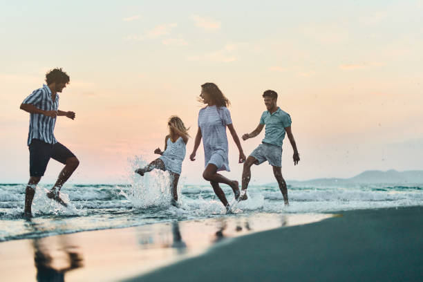 istock Cheerful couples having fun on the beach at sunset. 1446834345