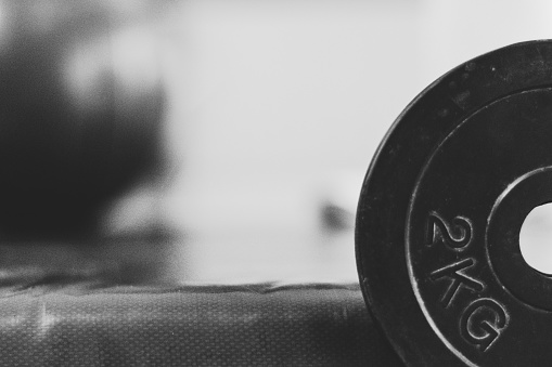 A grayscale shot of a 2kg dumbbell disc against a blurry background