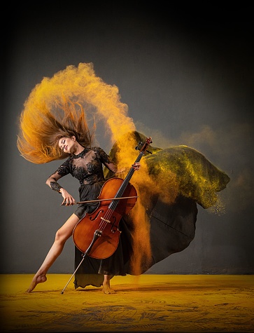 A Southeast Asian woman playing cello with yellow powder on her hair splashing around