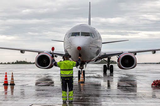 Airplane marshalling at the aiport apron in rainy weather. Passenger aircraft meeting at Chelyabinsk airport