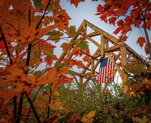 istock American flag hanging in a wooden structure surrounded by fall foliage 1446840517