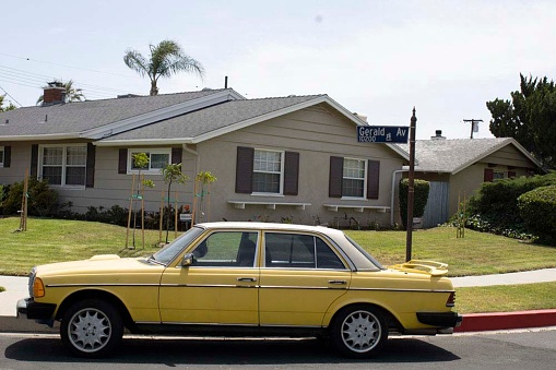 los angeles, United States – May 25, 2022: A vintage yellow Mercedes parked on the side of a road by a house in Northridge, Los Angeles