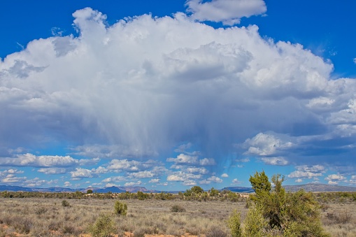 A giant, white rain cloud over the desert landscape.