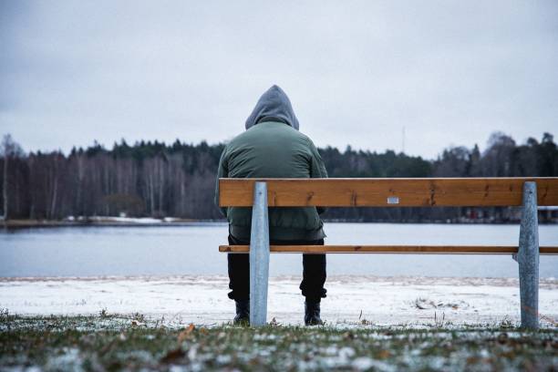 istock Lonely man sitting on the bench in a snowy park 1446843287