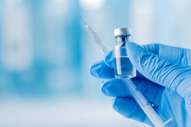 doctor's hand holding glass vial and syringe with injection over blue background. - syringe vaccination vial insulin imagens e fotografias de stock